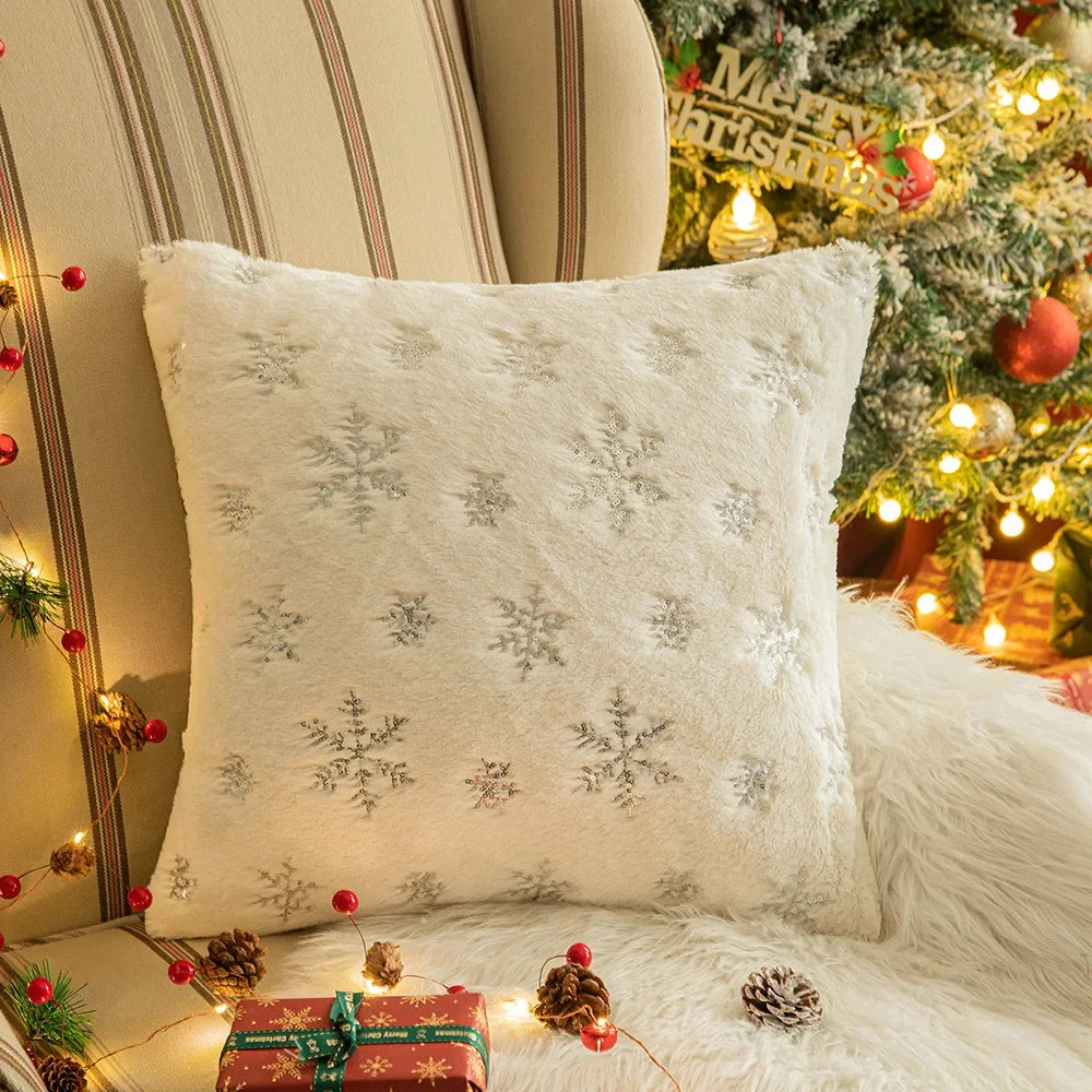 Housse de coussin déco Noël Snow Beige à flocons métallisés devant un sapin de Noël