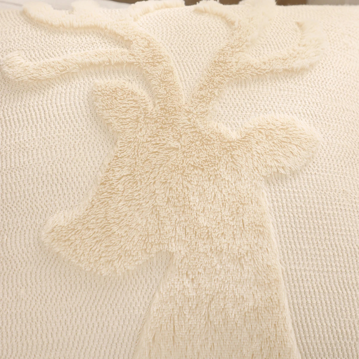 Gros plan sur la tête de renne en relief duveteux d'une housse de coussin de Noël Ivoire