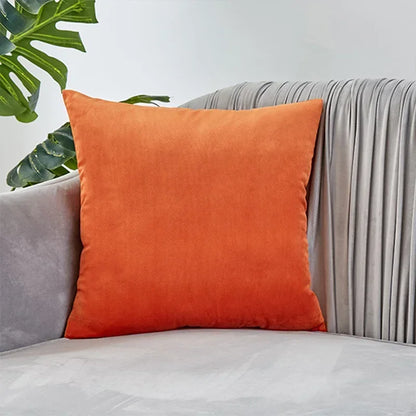 Housse de coussin Velours Lisse Orange posée sur un canapé gris