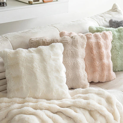 Assortiment de housses de coussin fausse fourrure Moumoute Beige, Rose Poudré, Blanc et Vert Menthe sous un plaid