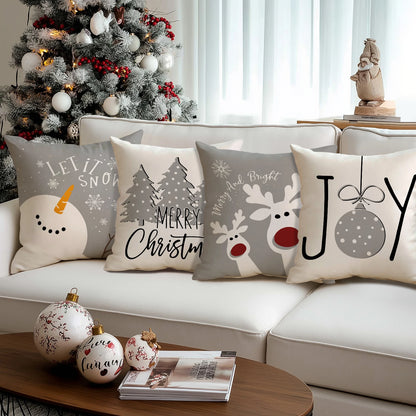 Housses de coussin de Noël Snowman, Pinetree, Rudolph et Joy alignées sur un canapé blanc avec des boules de Noël