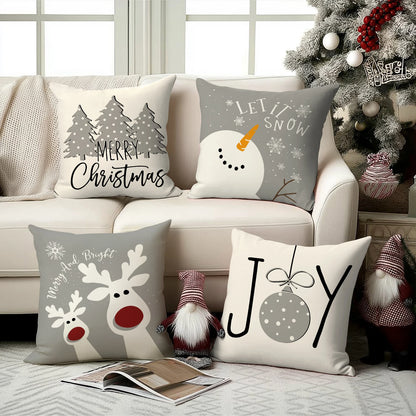 Quatre housses de coussin de Noël Gris et Beige posées sur un canapé clair devant un sapin
