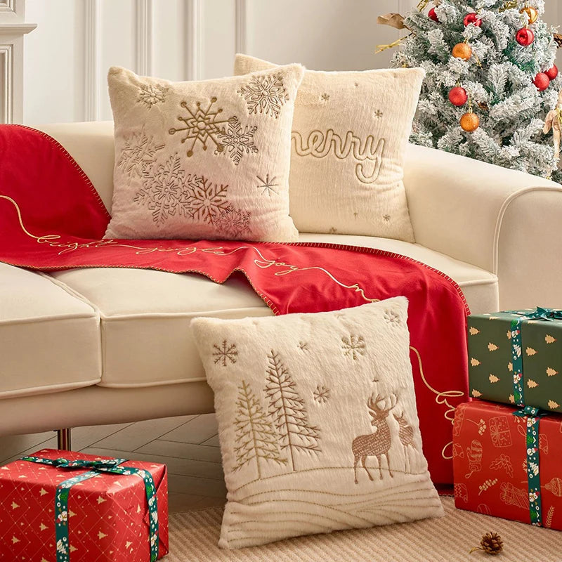 Housses de coussin de Noël Écru avec flocons, mot Merry et forêt aux cerfs en fil Doré sur un canapé