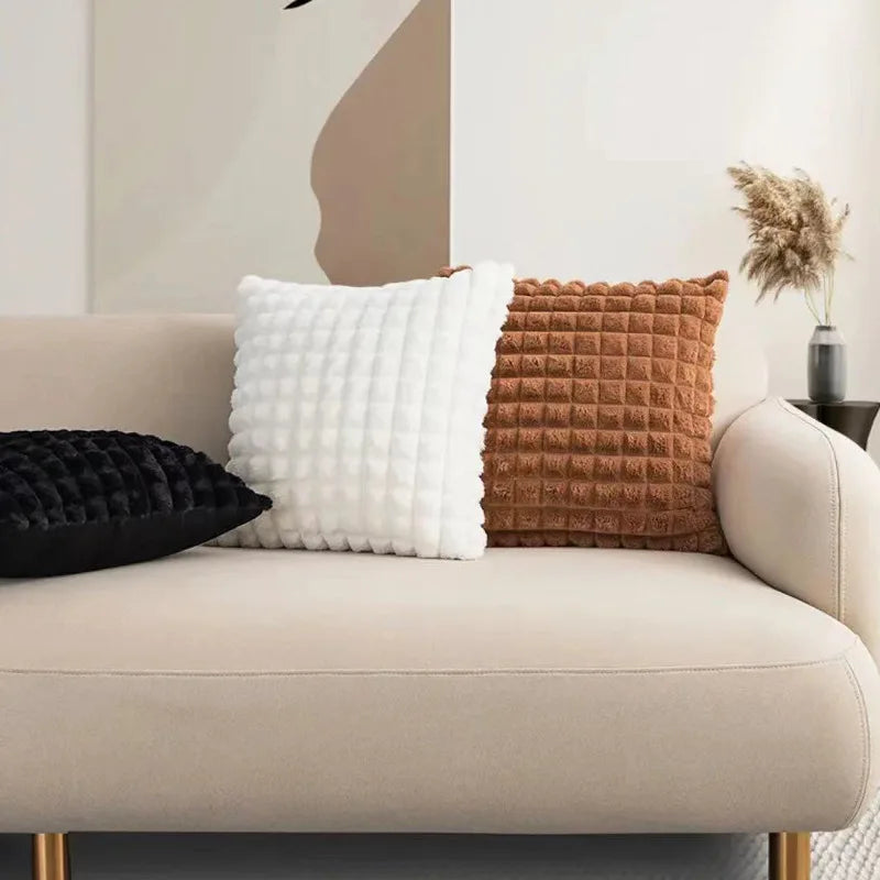 Housses de coussin Velours Gaufré Noir, Blanc et Camel alignées sur un canapé clair